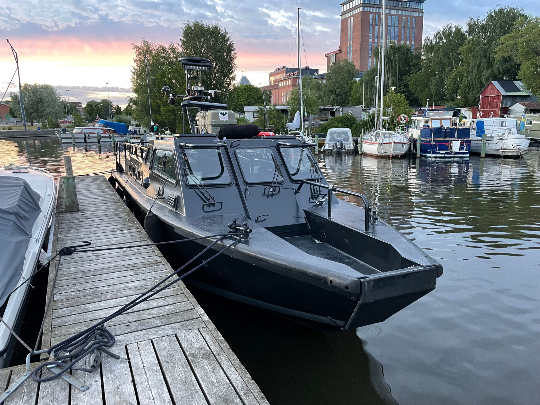 Mörk patrullbåt förtöjd vid bryggan i kvällsljus